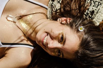 Close-up portrait of woman with glittering make-up lying on bed