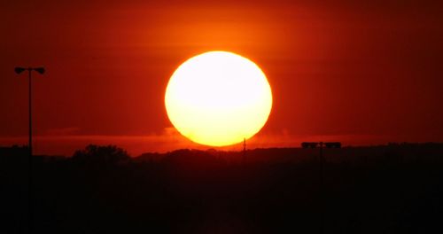 Scenic view of silhouette field against orange sky