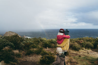 Mother with children looking at sea while standing on mountain