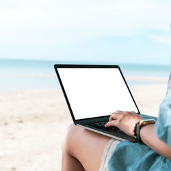 Midsection of man using mobile phone on beach