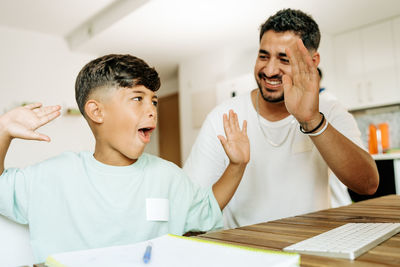 Homeschooling and freelancing. happy child son giving high five to mother while doing homework