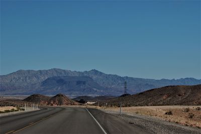 Empty road by mountains against clear blue sky in nevada 