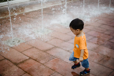 High angle view of boy looking away while standing on footpath