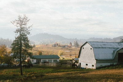 Houses on field by buildings against sky