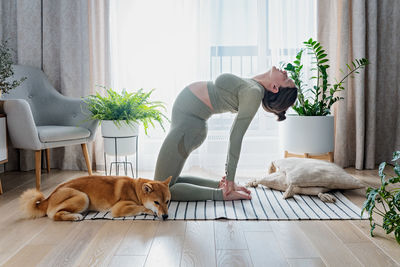 Pregnant female doing prenatal yoga at home in the brightly living room