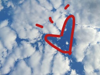Low angle view of red heart shape against sky