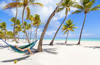 Dominican rebublic, young woman lying in hammock on tropical beach