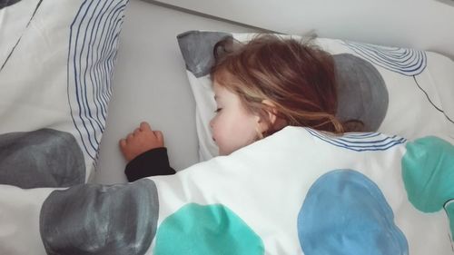 High angle view of cute girl sleeping on bed at home