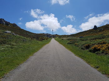 Road amidst green landscape against sky