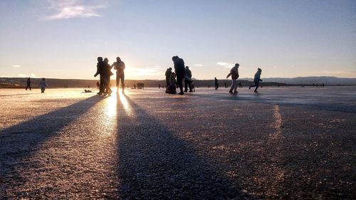 Silhouette people at beach against sky during sunset