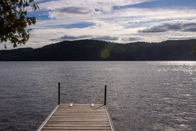 Pier over lake against sky during sunset