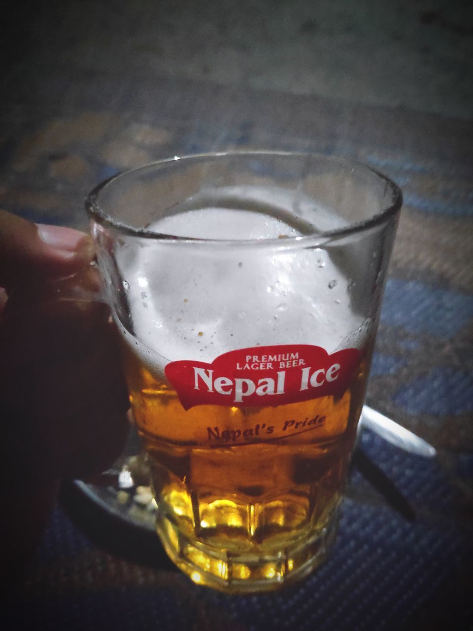 CLOSE-UP OF HAND HOLDING GLASS OF BEER IN GLASSES