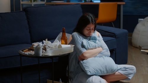 Young woman using mobile phone while sitting on sofa at home