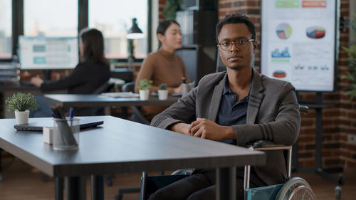 Portrait of young businessman sitting on wheelchair at office