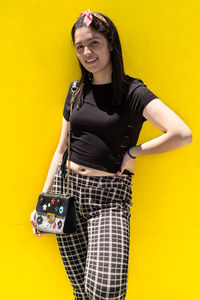 Portrait of smiling girl standing against yellow background