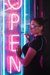 Side view of woman standing against illuminated text