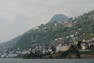 Aerial view of townscape by mountain against sky