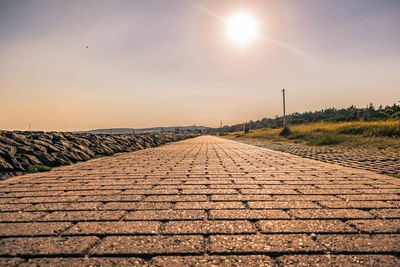 Low angle view of a straight empty road against sky during sunset