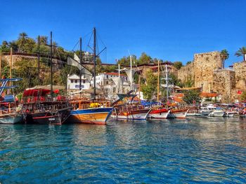 Boats moored at harbor against clear blue sky