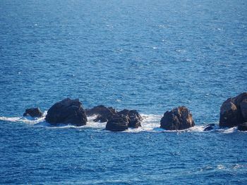 Rock formation in sea against blue sky