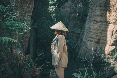 Woman standing by tree trunk in forest