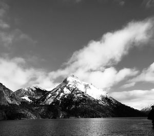 Scenic view of lake by snowcapped mountains against sky