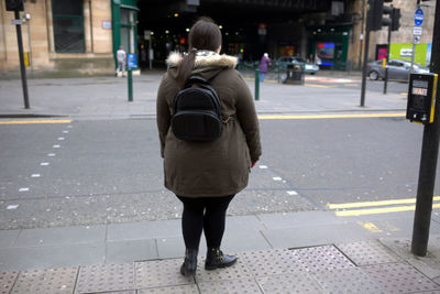 Rear view of woman with bag standing on city street