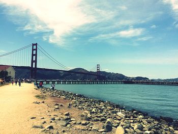 Bridge over sea against cloudy sky