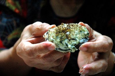 Close-up of person's hand  holding baked oyster