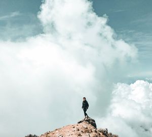 Low angle view of man standing on rock against sky