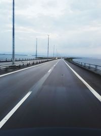 Road leading towards highway against sky