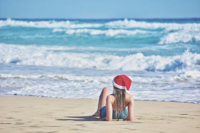 Rear view of woman relaxing on sand at beach