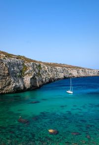 Sailboat in sea against clear blue sky