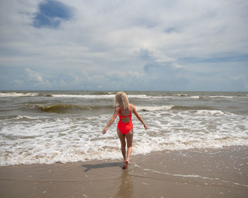 Full length rear view of man on beach against sky