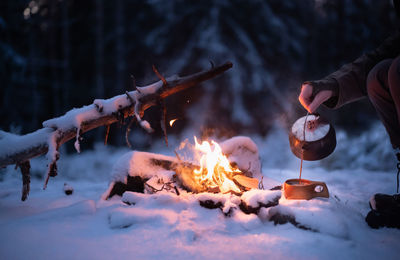 Pouring coffee made on a campfire into a wooden cup. snowclad forest environment