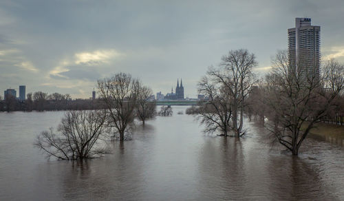 Scenic view of river by city against sky during winter