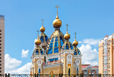 Golden domes of a christian church on glass roof facades among an urban residential area.