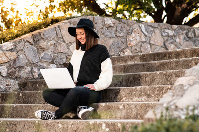 Young woman using laptop while sitting on steps