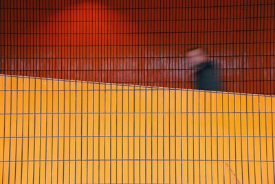 Blurred motion of man walking by tiled wall