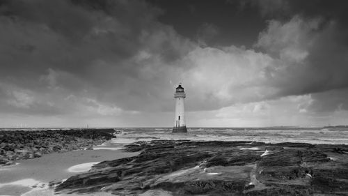 Lighthouse by sea against sky