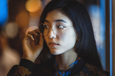 Close-up portrait of young woman holding eyeglasses