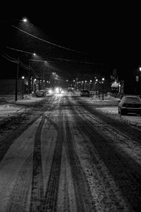 Illuminated tire tracks against sky at night during winter