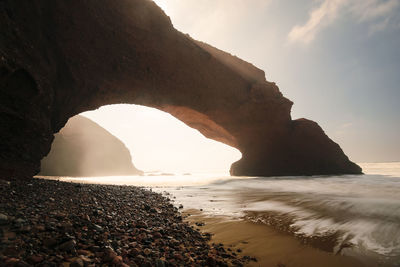 Scenic view of rock formation in sea against sky