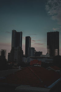 Modern buildings in city against sky at sunset