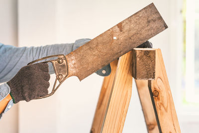 Cropped hands of carpenter cutting wood in workshop