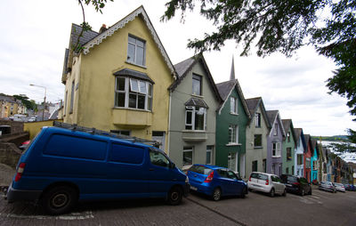 Cars on street by buildings against sky