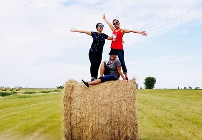 Full length of friends standing on field against sky