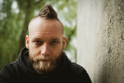 Portrait of man with spiky hair by wall