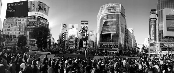 Panoramic view of crowd on city street by buildings