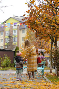 Rear view of people walking on autumn leaves